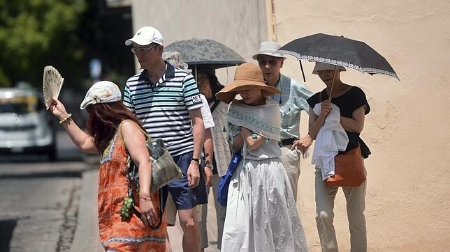 Un grupo de turistas se tapan con sombrillas y pañuelos para seguir su visita por Córdoba