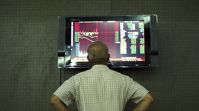 Un inversor sigue la evolución de la Bolsa en una pantalla en una casa de corretaje en Pekín