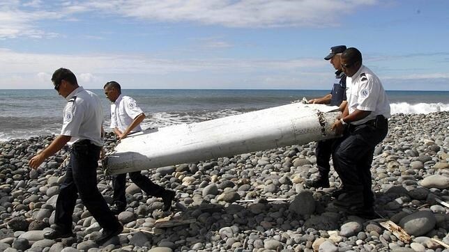 Varios policías trasladan los restos de avión encontrados en La Reunión