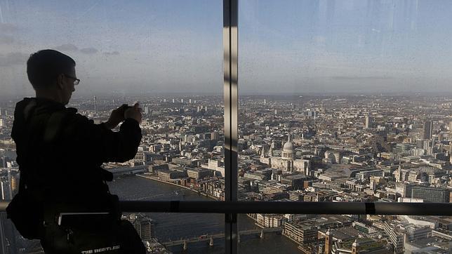 Un hombre hace fotos de Londres desde un edificio junto al río Támesis
