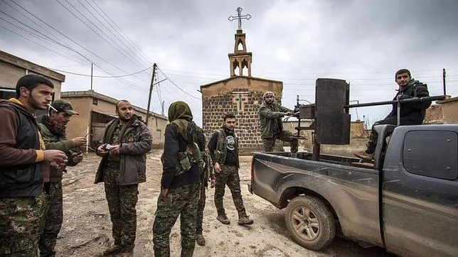 Un grupo de militares kurdos junto a una iglesia asiria en Al Hasaka, Siria