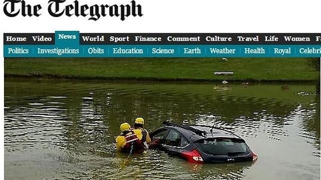 Un hombre mayor se pone a fumar pipa mientras su coche se hunde en un lago