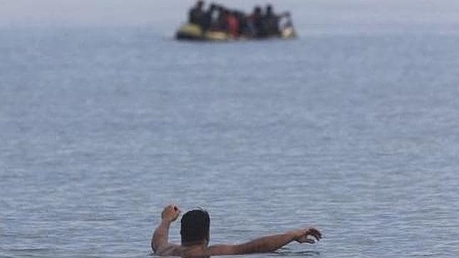 Un hombre en la playa observa la llegada de una lancha con inmigrantes en la isla griega de Kos.