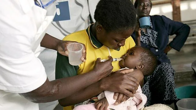 Una enfermera le administra agua con azúcar a un niño enfermo de cólera de Zimbabue