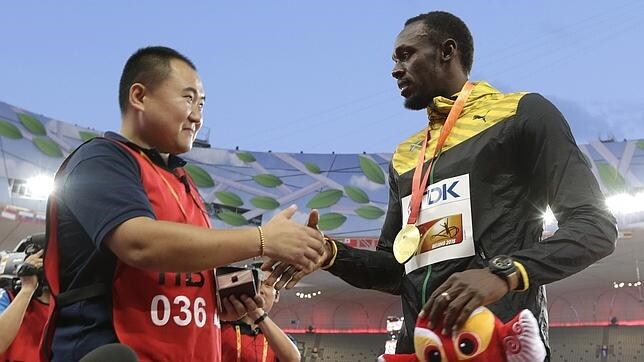 Song Tao y Usain Bolt estrechan las manos tras la ceremonia de entrega de medallas