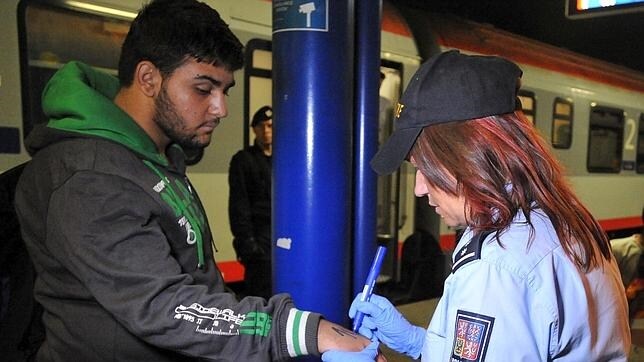 Oficial trazando un número en la palma de un refugiado