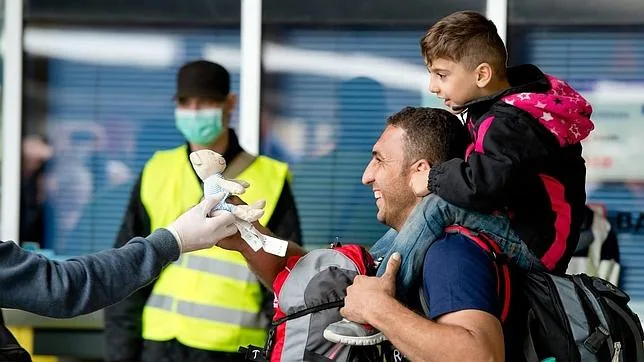 Unos refugiados reciben un juguete a su llegada a Múnich