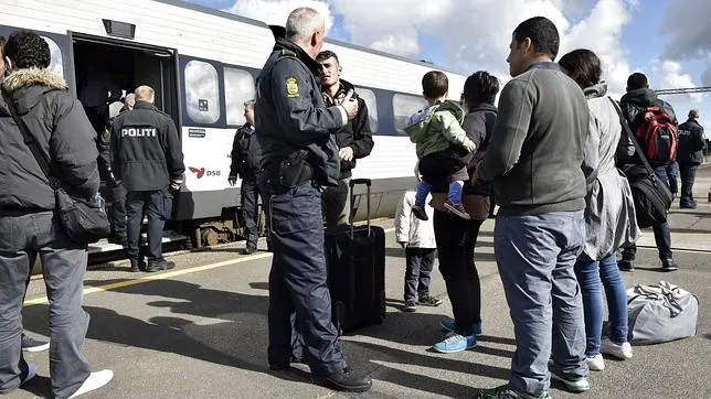 Un policía danés habla con refugiados procedentes de Alemania a su llegada a la ciudad de Rodby