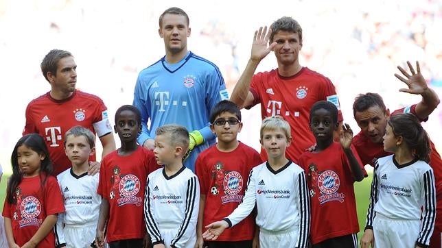 Los jugadores del Bayern Múnich de saltan al campo de la mano de niños refugiados