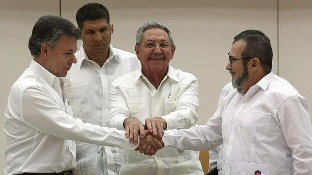 El presidente de Cuba, Raúl Castro (cen), aprieta las manos del presidente de Colombia Juan Manuel Santos (izq) y el máximo líder de las FARC, Rodrigo Londoño (der), alias "Timochenko"
