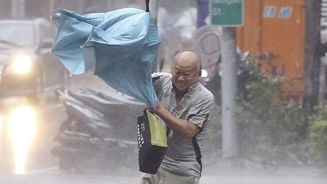 Un hombre lucha contra el viento causado por el tifón Duajuan en Taipei (Taiwán)