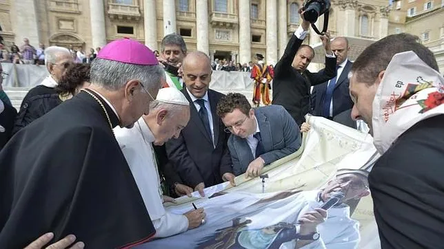 El Papa Francisco firma una fotografía suya durante la audiencia general de los miércoles en la Plaza de San Pedro