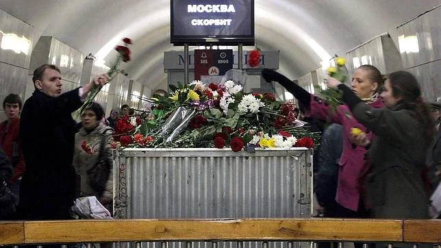 Varios viajeros depositan flores en memoria de las víctimas en la estación de metro de Lubyanka, en Moscú