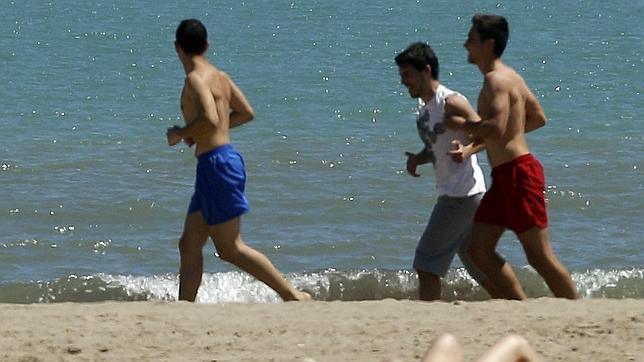 Varios jóvenes disfrutan por una playa valenciana