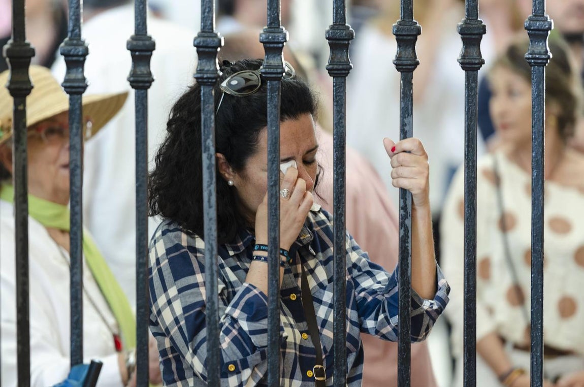 Una mujer llora mientras le reza a la Virgen agarrada a su reja