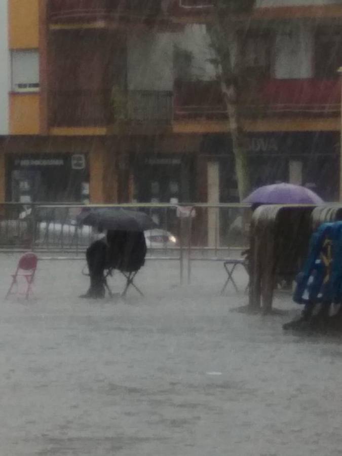 Un hombre espera bajo su paraguas la salida de la Macarena