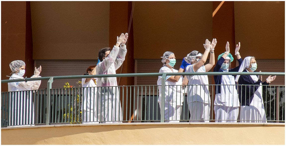 Domingo de Ramos. Procesión de palmas.. Los trabajadores de una residencia geriátrica aplauden a los ancianos del edificio contiguo que permanecen en confinamiento por la pandemia del coronavirus.