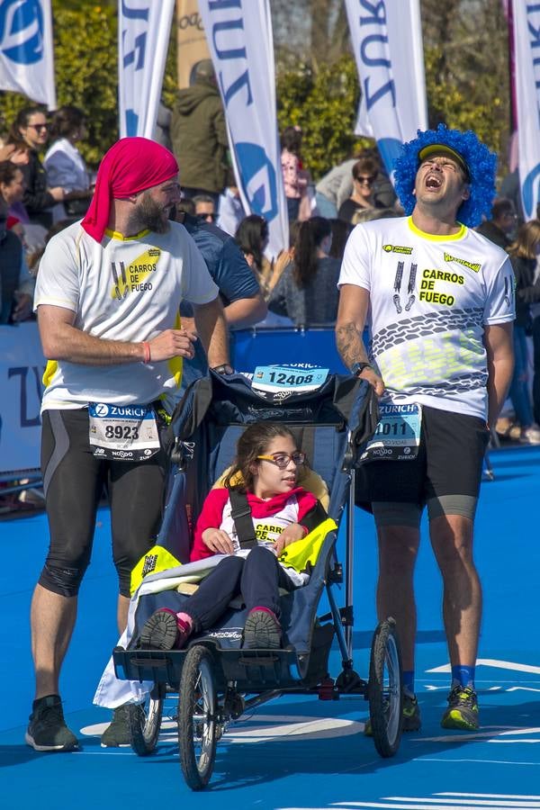 Lunes Santo. Los Dolores (Las Penas). Un integrante de la Asociación Carros de Fuego se retuerce de dolor mientras se esfuerza por continuar corriendo y empujando la silla adaptada a escasos metros de llegar a la meta del Maratón de Sevilla. Esta asociación proporciona, a través de sus voluntarios deportivos, actividades para niños con Diversidad Funcional, al tiempo que intenta visibilizar al colectivo de personas con diversidad funcional para sensibilizar a la población y concienciar sobre sus recursos y necesidades.