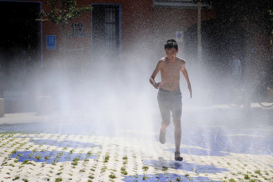 Lunes Santo. Las Aguas. Un chaval se divierte y se refresca en los difusores de agua de la Alameda de Hércules para combatir el calor.