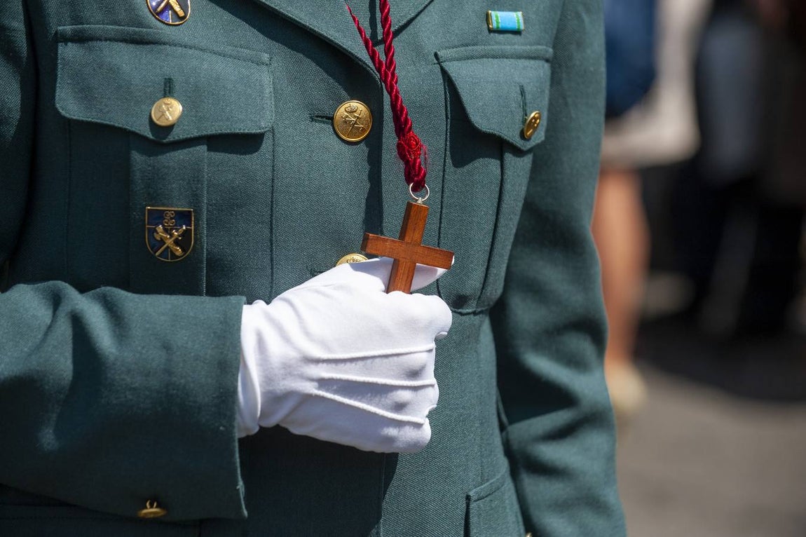 Martes Santo. Santa Cruz. Un Guardia Civil de uniforme sujeta con fuerza con su mano enguantada la cruz de madera que cuelga de su cuello.