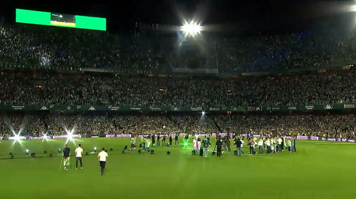 Abajo a la izquierda, con polo oscuro y muletas, Camarasa es acompañado en todo momento por Fernando, con polo blanco, mientras el resto del equipo celebra la Copa en el Villamarín