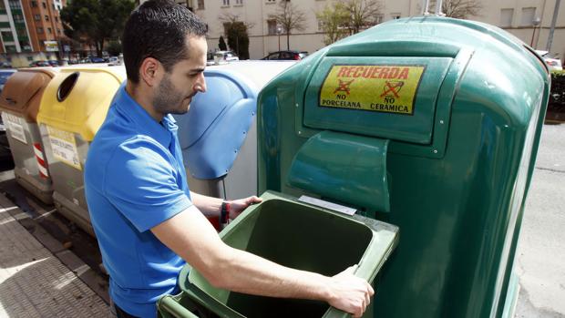 Un hombre vierte la basura de una papelera en un contenedor