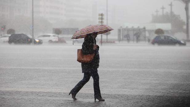 Una viandante cruza la plaza de las Tres Culturas en plena lluvia