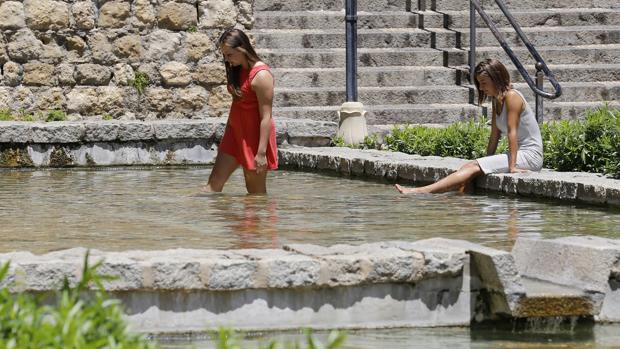 Dos jóvenes se refrescan en una fuente