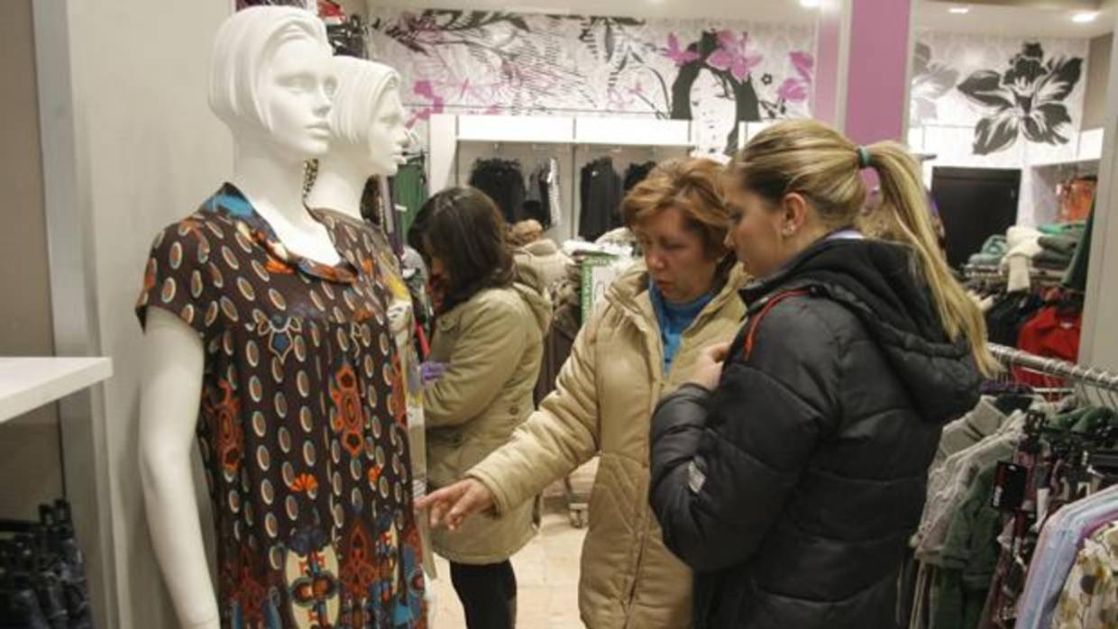 Dos clientas miran prendas de ropa en un negocio de moda