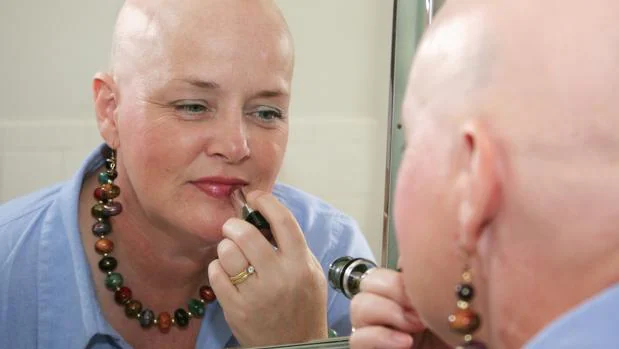 Una paciente oncológica se maquilla frente al espejo