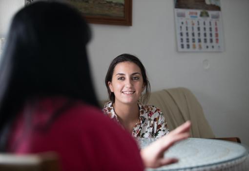 María, de espaldas, con Olga, trabajadora social de Cáritas