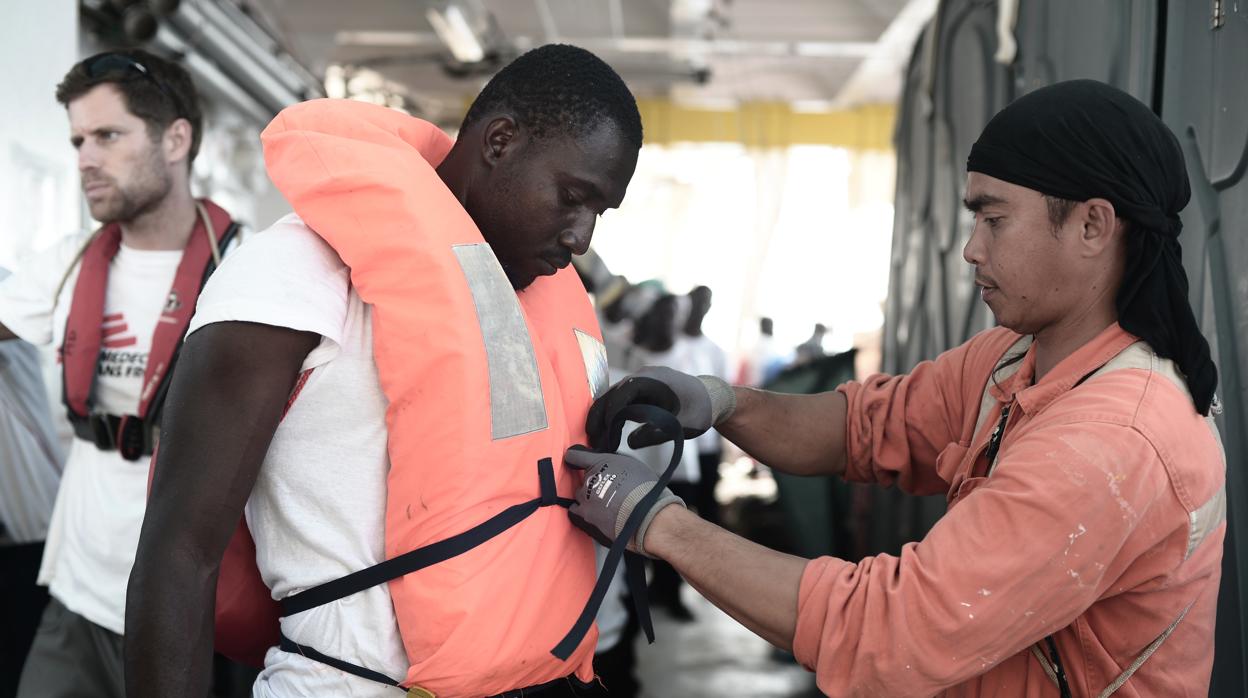 Un voluntario ayuda a un inmigrante en el buque «Aquarius»