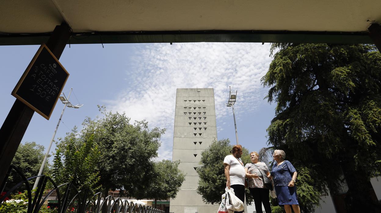 Tres vecinos delante del campanario del barrio que simula las Tablas de Moisés