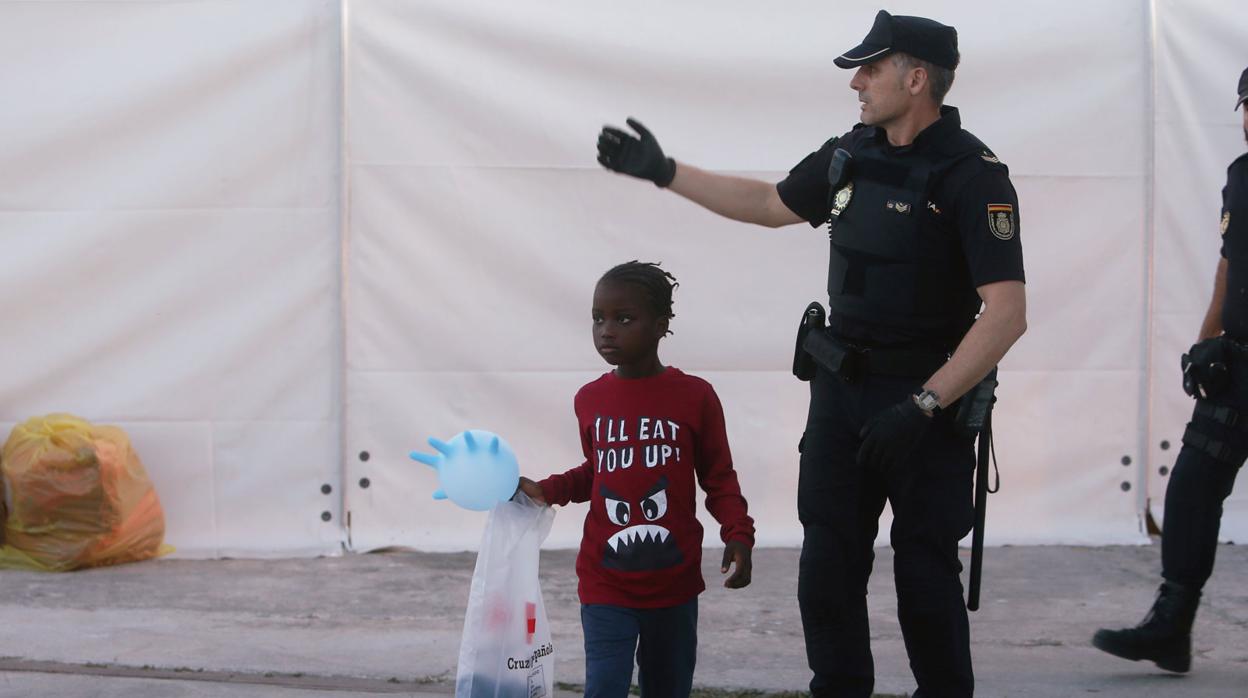 Un menor inmigrante junto a un agente de la Policía Nacional