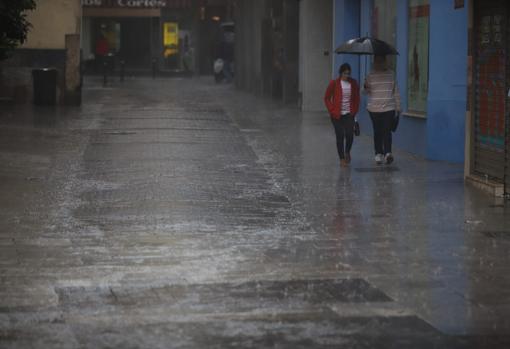 Dos personas pasean por el centro de la ciudad protegidas con paraguas