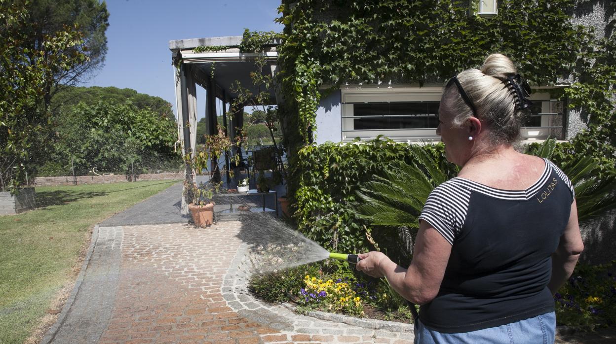 Una vecina de las Jaras riega el jardín con una manguera