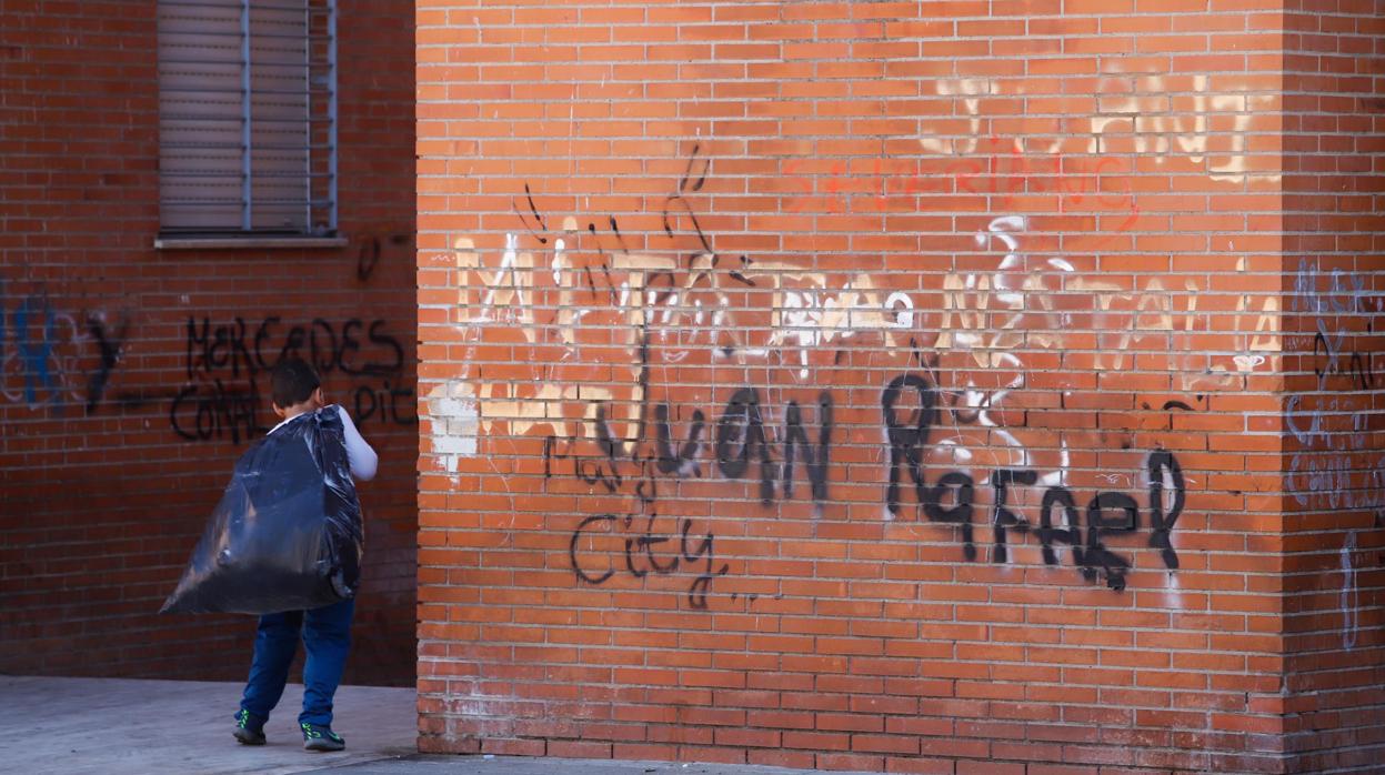 Un menor saca la basura en Moreras en un bloque con pintadas en la fachada
