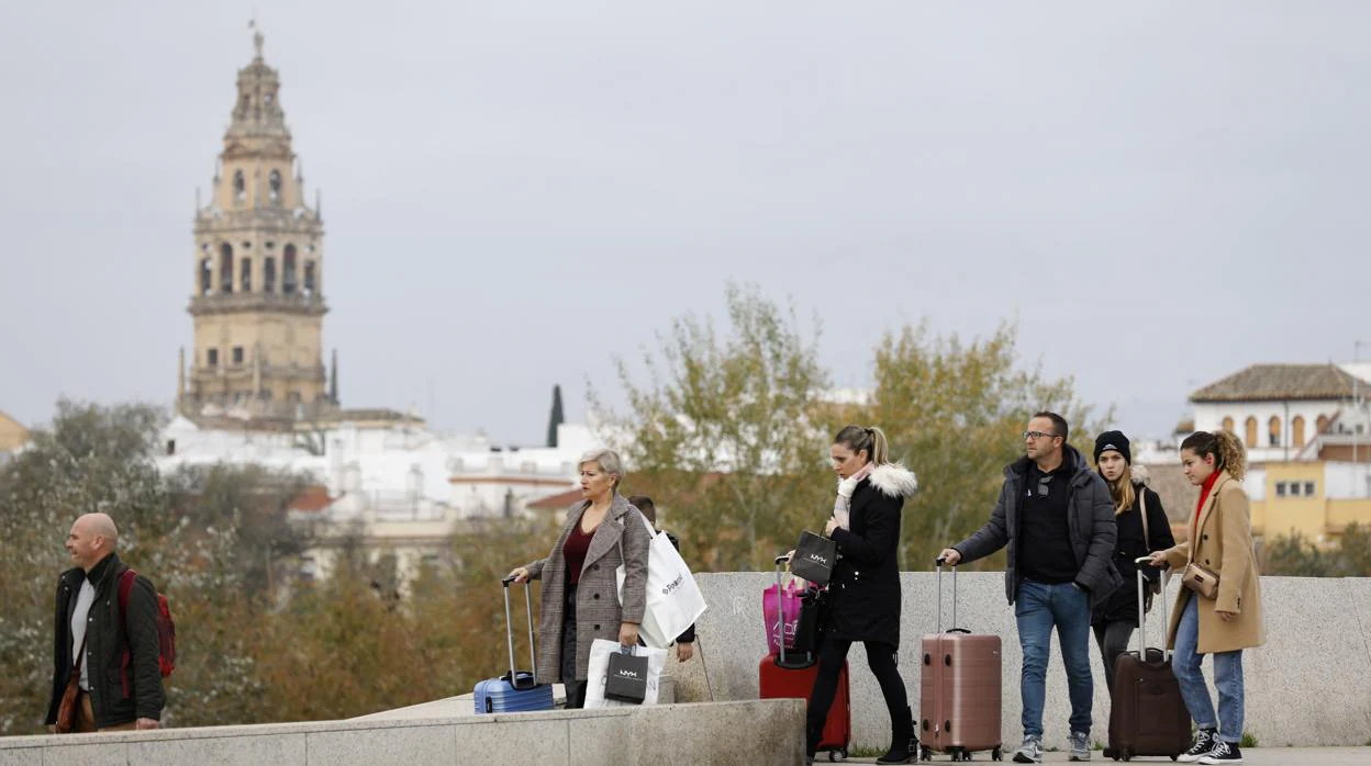 Turistas con maletas en el Puente de Miraflores, con la torre de la Mezquita-Catedral de fondo