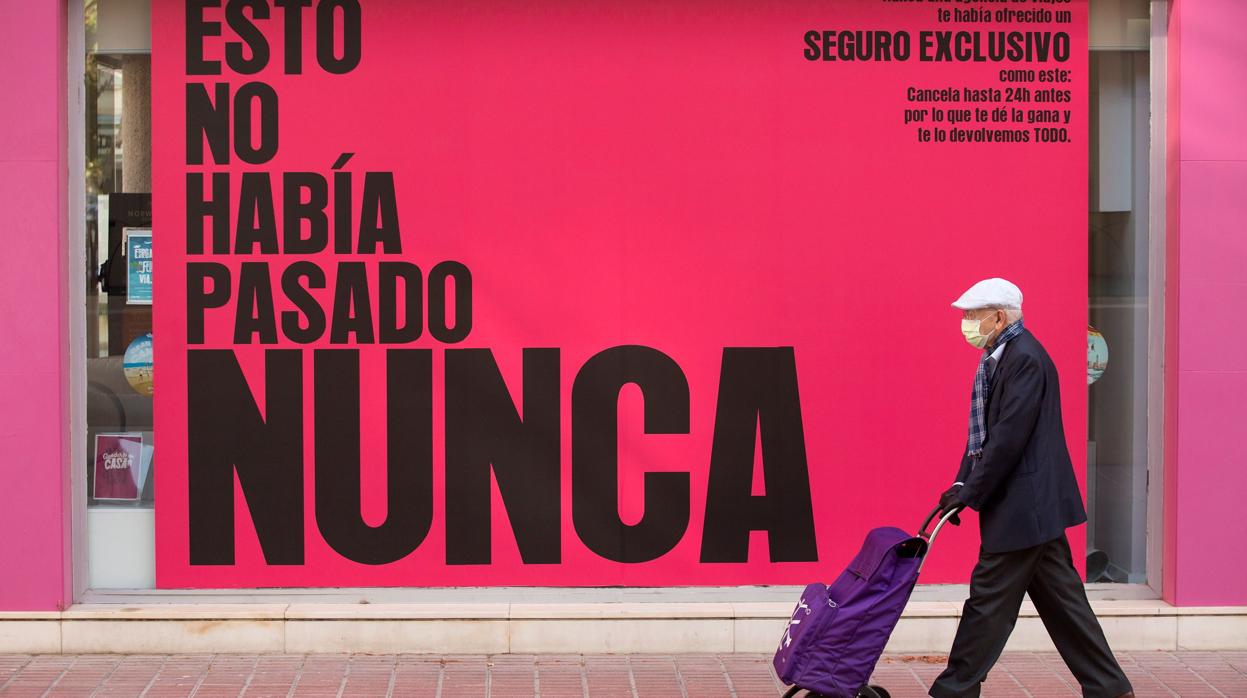 Una persona protegida con una mascarilla pasa por delante de una agencia de viajes en Málaga
