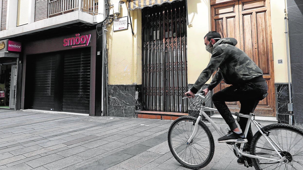 Un ciclista pasa por el negocio cerrado de la taberna Correo, en Jesús y María