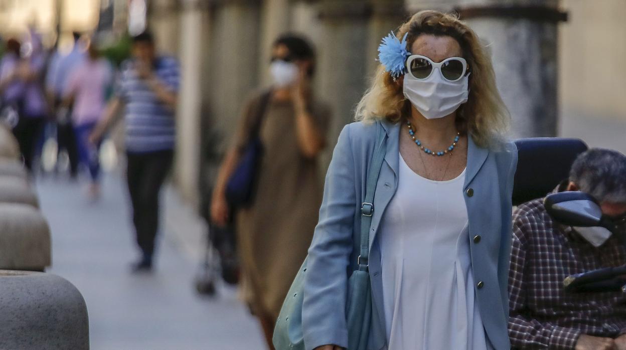 Una mujer camina por las calles de Sevilla con una mascarilla