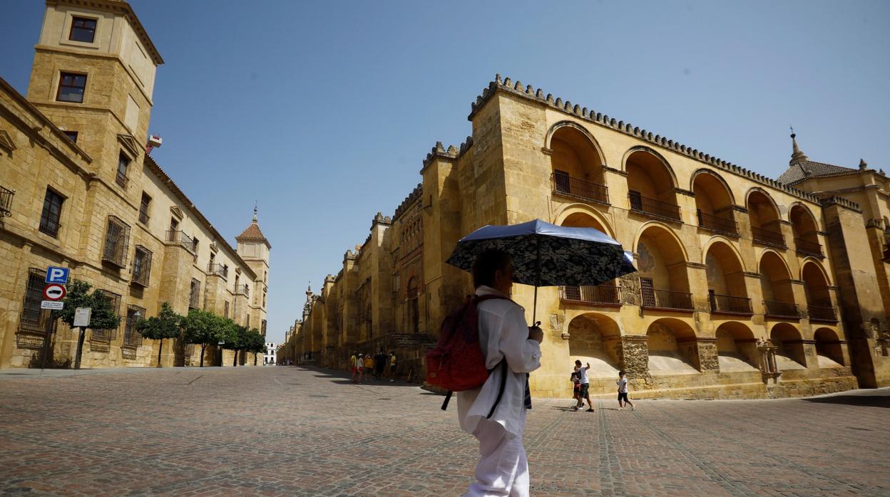 Una turista pasa junto a la Mezquita-Catedral de Córdoba protegida por un paraguas