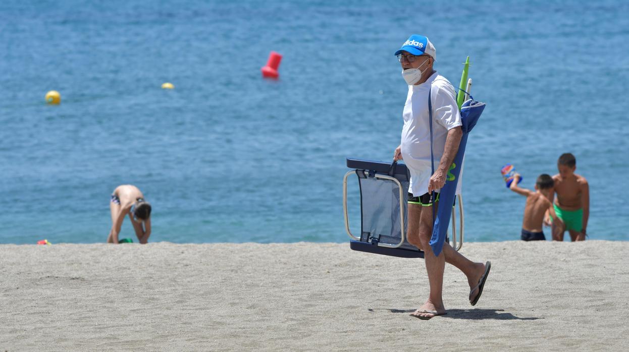 Un hombre con mascarilla camina por la playa de El Zapillo en Almería