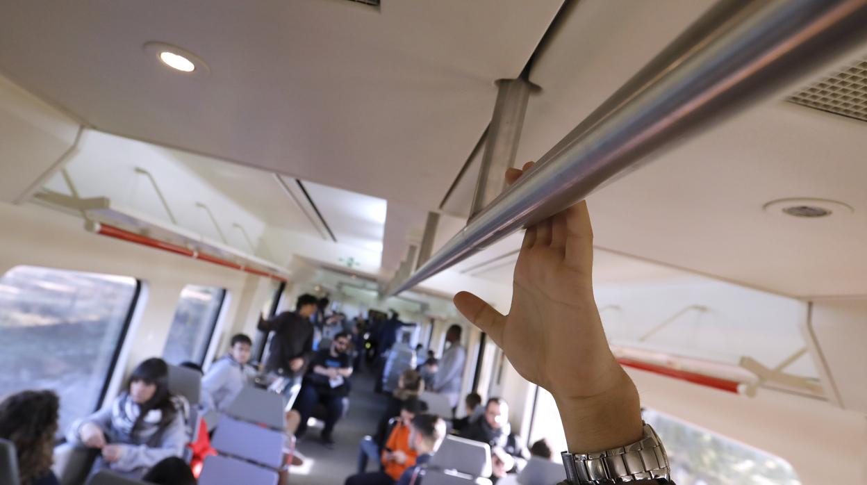 Un usuario del servicio ferroviario se agarra a una barra en alto