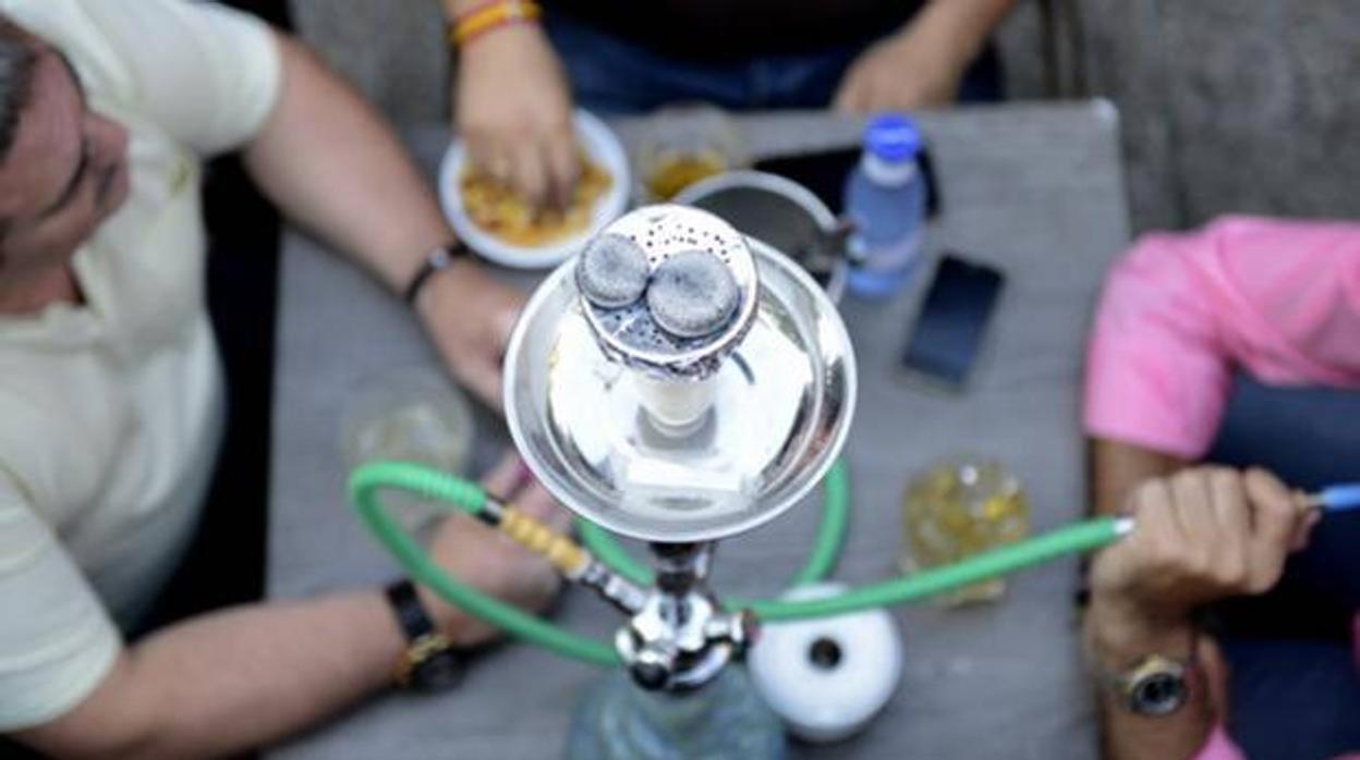 Varios jóvenes fumando en una cachimba