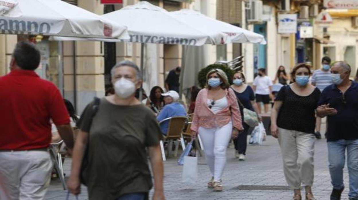 Vecinos de Sevilla paseando por la calle con mascarilla