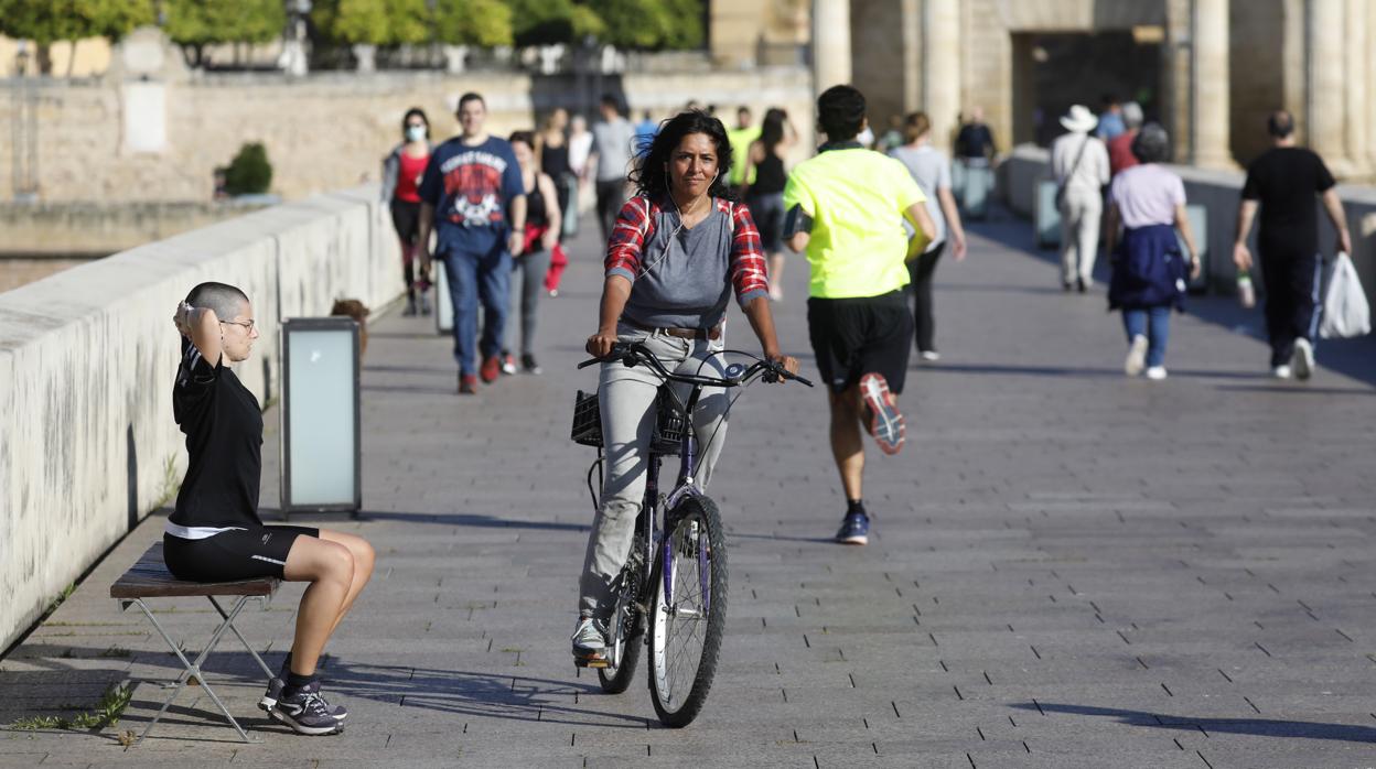 Una mujer circula en bicicleta por el Puente Romano de Córdoba