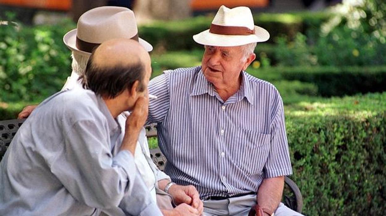 Tres personas mayores sentados en un parque departiendo