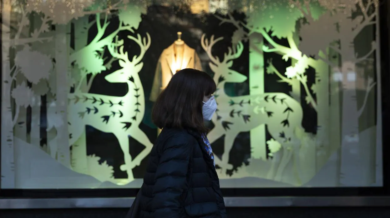 Una mujer pasa por delante de un escaparate decorado con motivos navideños