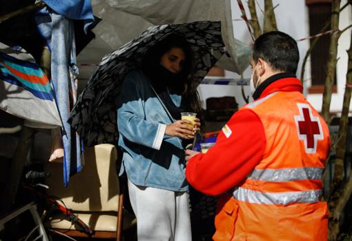 Un voluntario de Cruz Roja de Córdoba da una bebida a una mujer sin hogar